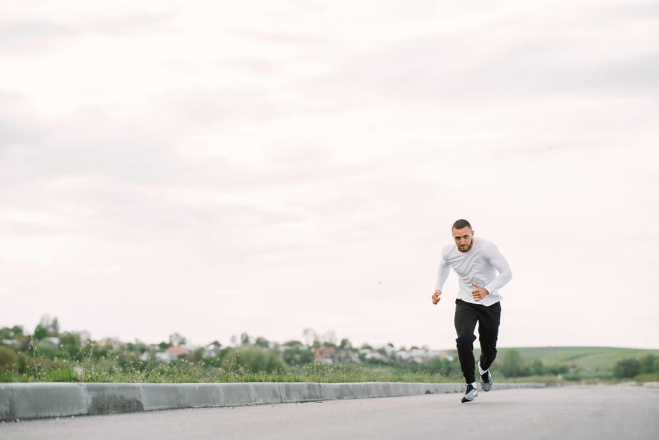 A man in sportswear jogging on a road, showcasing outdoor fitness.