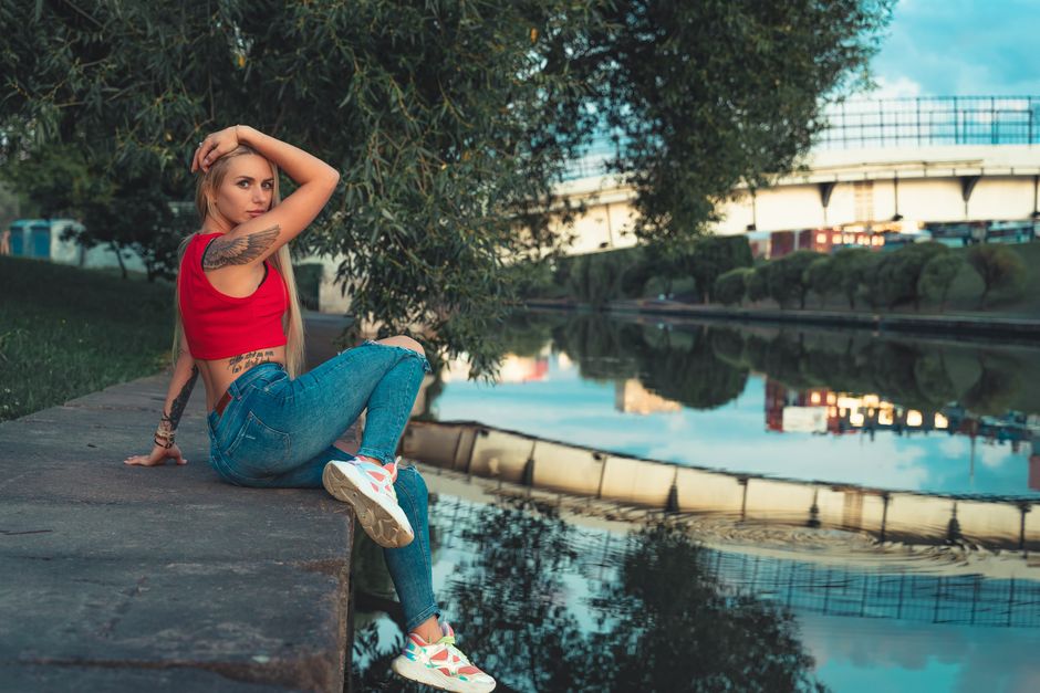 Young woman in casual attire posing by the river in Minsk. Vibrant and relaxed atmosphere.