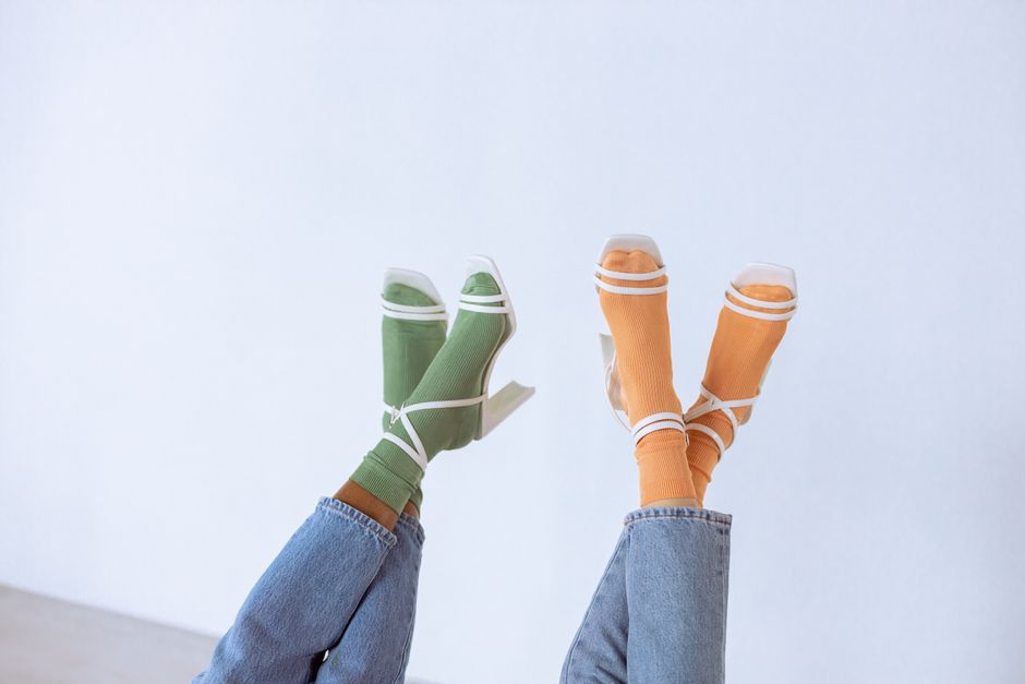 Upside down fashion photography featuring colorful socks with white heels on a white background.