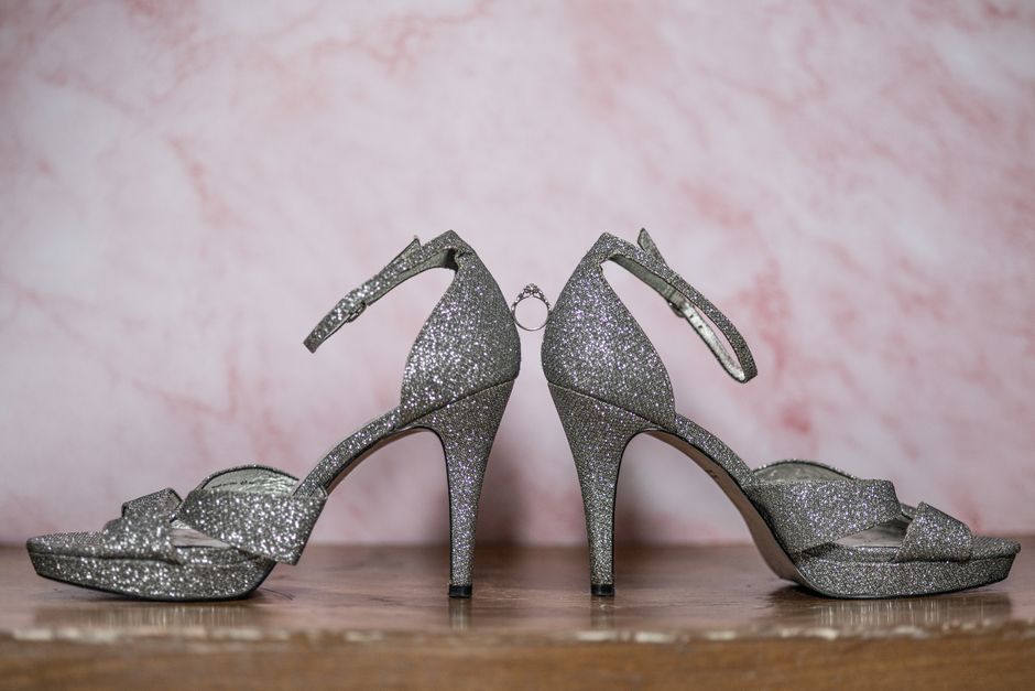 Elegant pair of glittery silver high heel shoes showcased on a wooden surface.