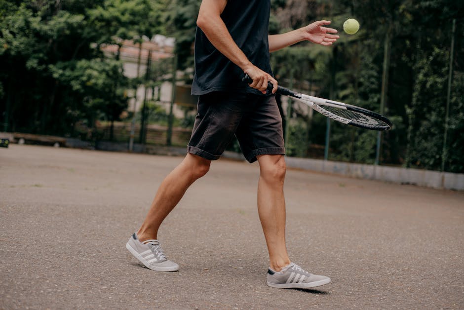 Close-up of a tennis player practicing on an outdoor court, ready to serve.