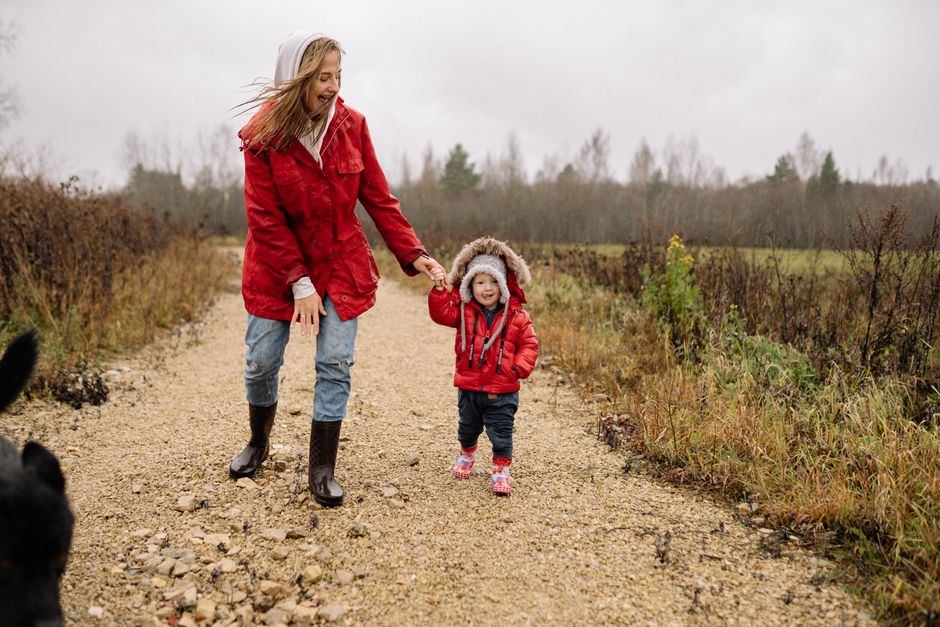 A cheerful mother and child walking on a rainy day in the countryside, sharing joyful moments.