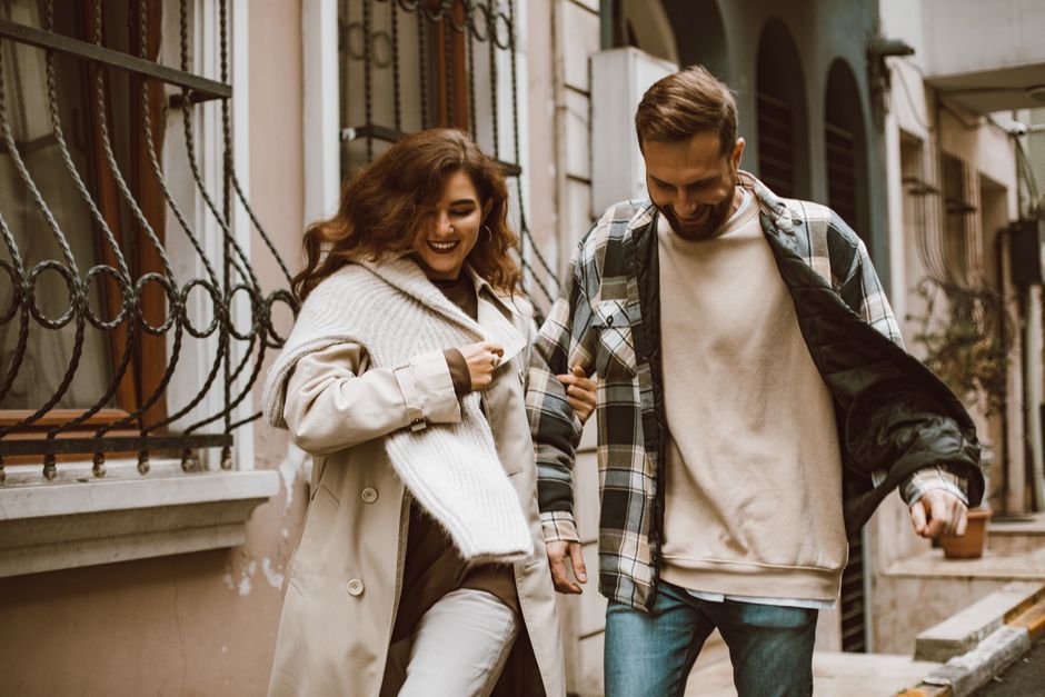 Joyful couple walking arm in arm down an urban street, smiling and enjoying their day.