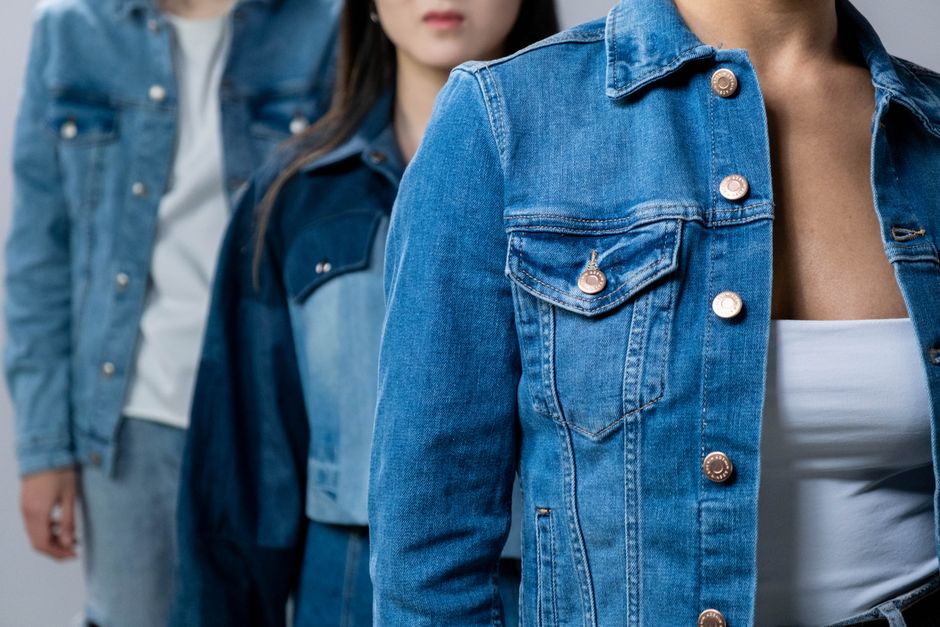Group of people modeling stylish denim jackets in studio setting.