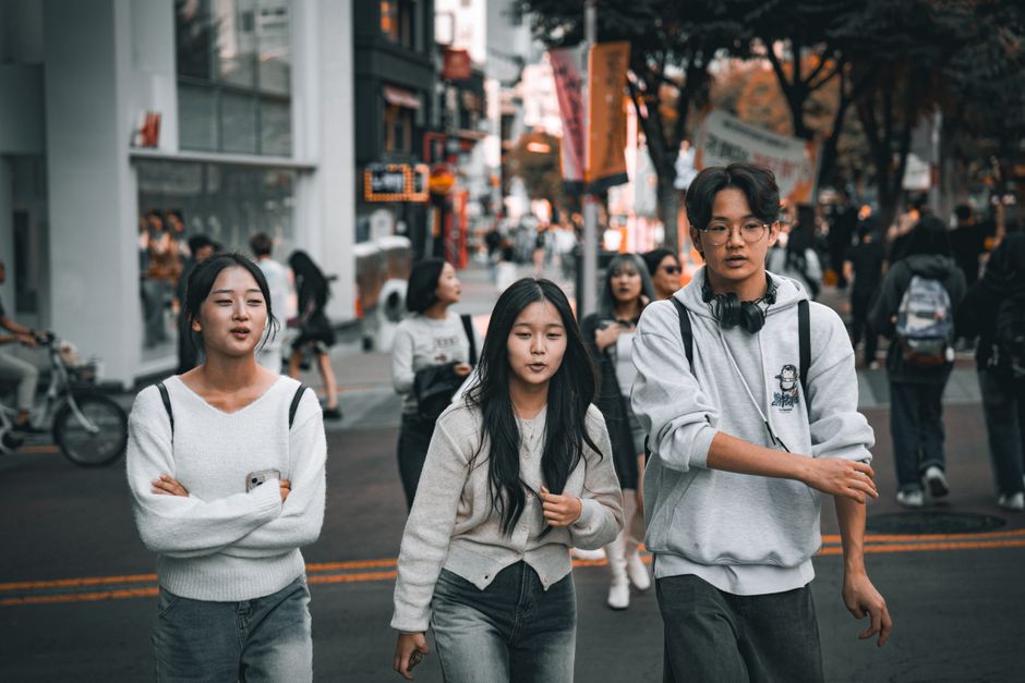 Group of young friends strolling through a lively street in Seoul, showcasing urban youth