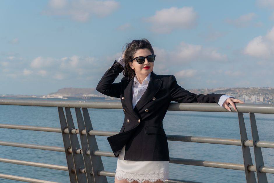 Woman in black blazer and sunglasses relaxing by the Caspian Sea in Baku.