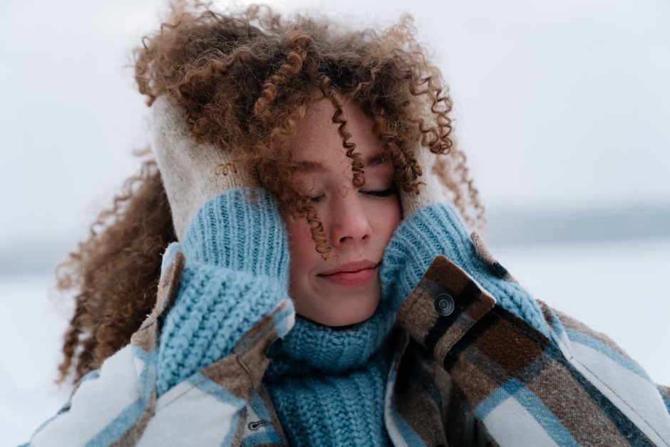 Portrait of a woman with curly hair enjoying winter outdoors with warm clothing.
